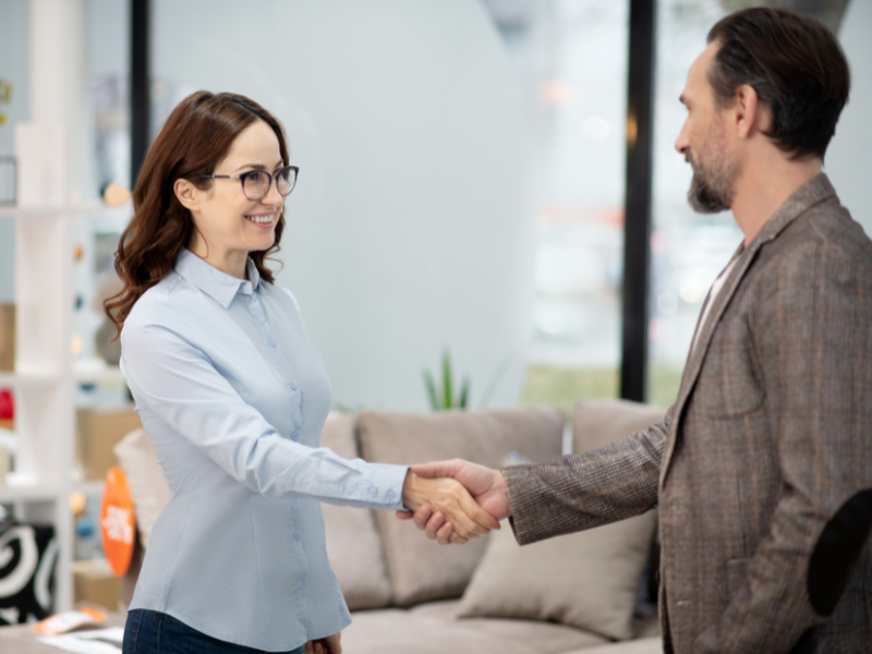 A man and a woman in a business setting shake hands