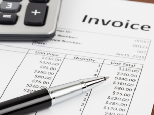 The upper right corner of an invoice, a pen, and a calculator