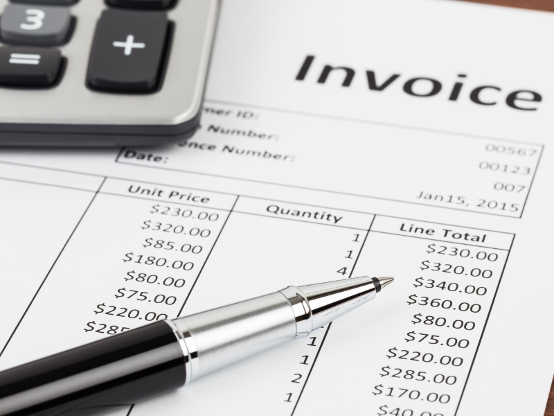 The upper right corner of an invoice, a pen, and a calculator