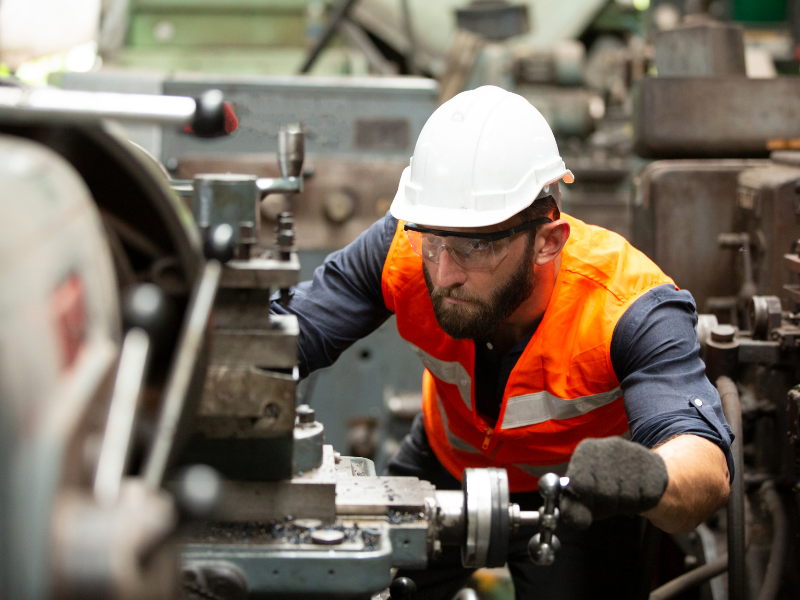 A factory worker using manufacturing equipment
