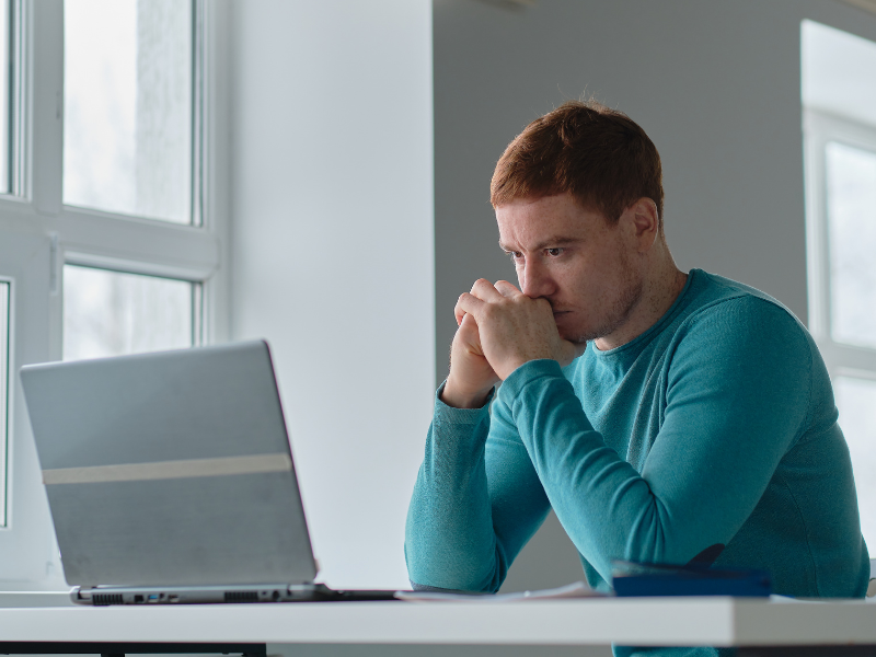 Stressed man reading ATO notice from his laptop