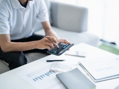 A man looking at a calculator, working out if business loan repayments are tax deductible
