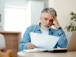 A stressed man reading a document, Employer reviewing payroll with super obligations