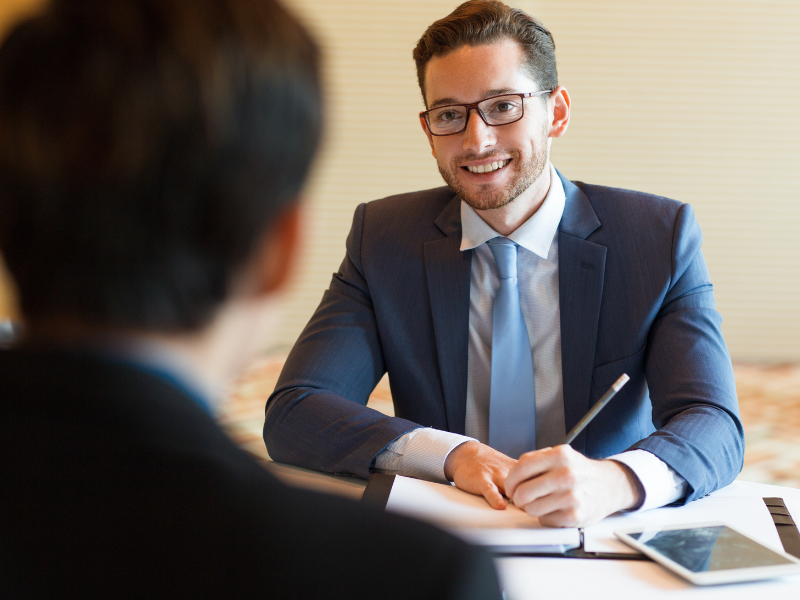 A professional business owner sitting with a broker or accountant reviewing loan documents